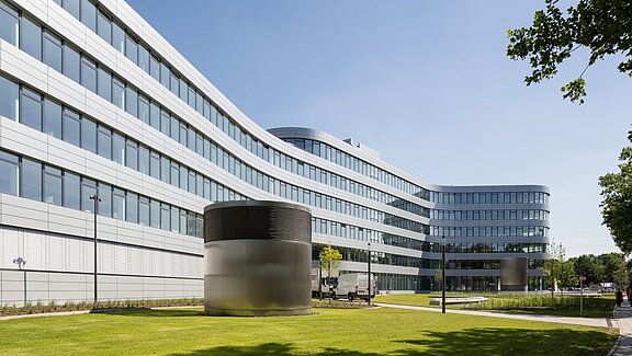 Langes Bürogebäude, davor grüne Wiese