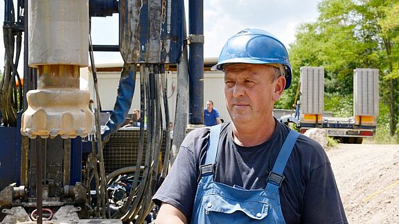 Bauarbeiter neben Bohrgerät mit Bohrkopf